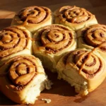 Freshly baked sourdough discard cinnamon rolls drizzled with caramel glaze, placed on a wooden countertop with warm natural lighting.